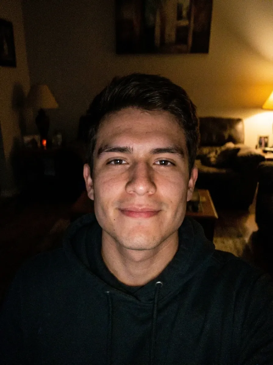 Original selfie input — young man in a dark hoodie in low light